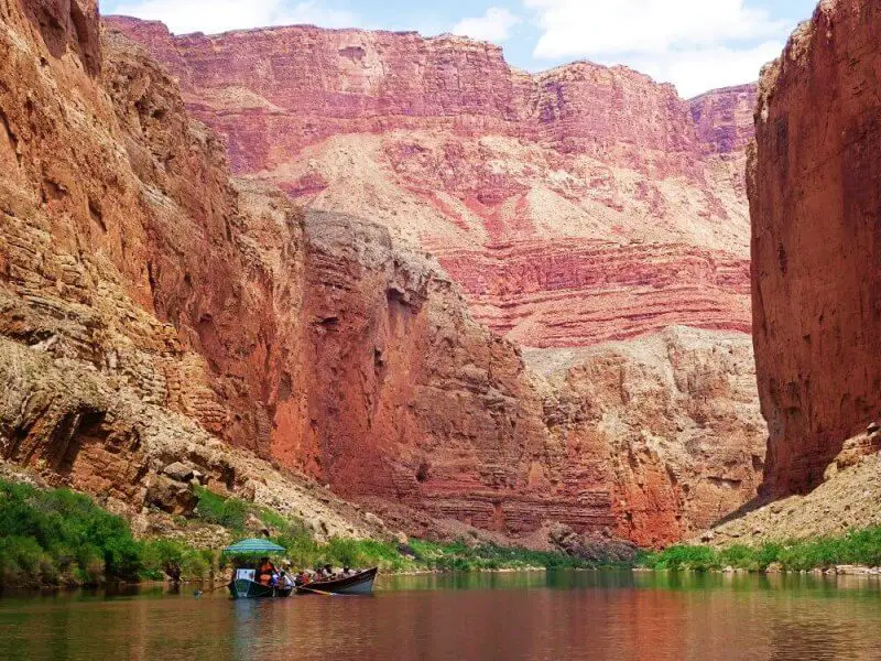 wooden boat with umbrella on calm river in large canyon  on river trip through grand canyon