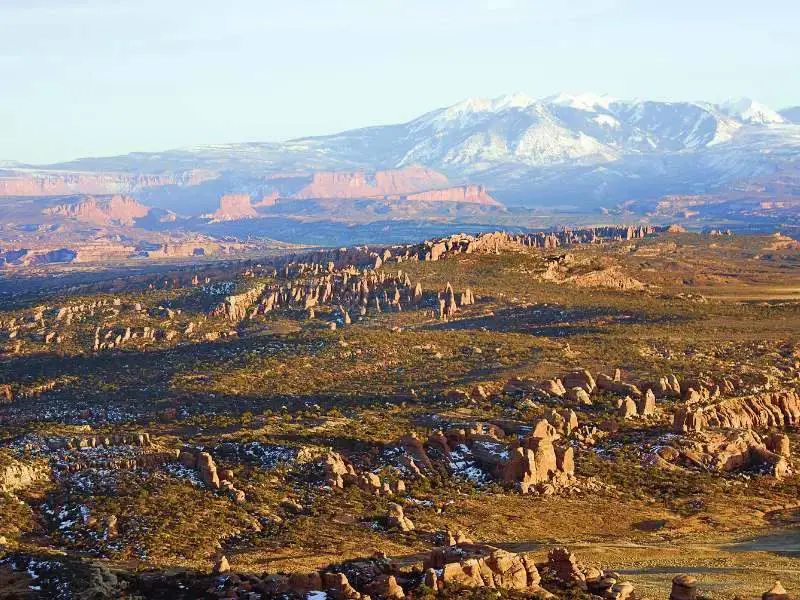 Aerial photo of rock formation in arches national park and behind is a snow capped mountain.