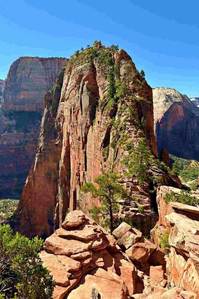 tall cliff with drop offs on both sides and tiny hikers walking up 