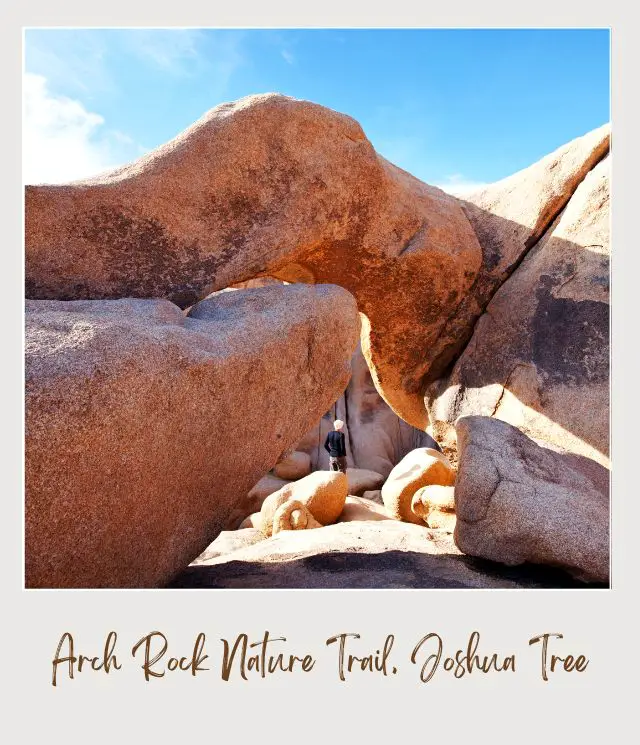 View of a man and a huge rock forming arch in Arch Rock Nature Trail, Joshua Tree National Park.