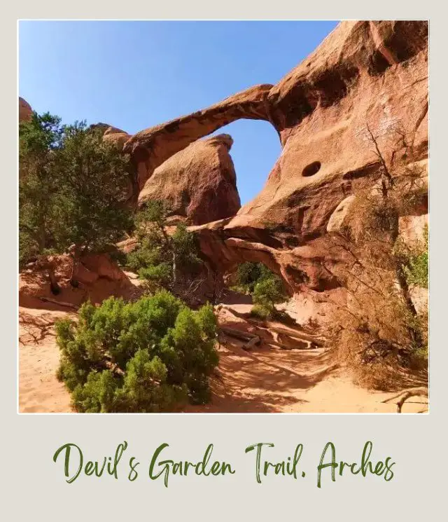 View from below of a Huge rock arch surrounded by other rock formations on Devils Garden Trail in Arches National Park.