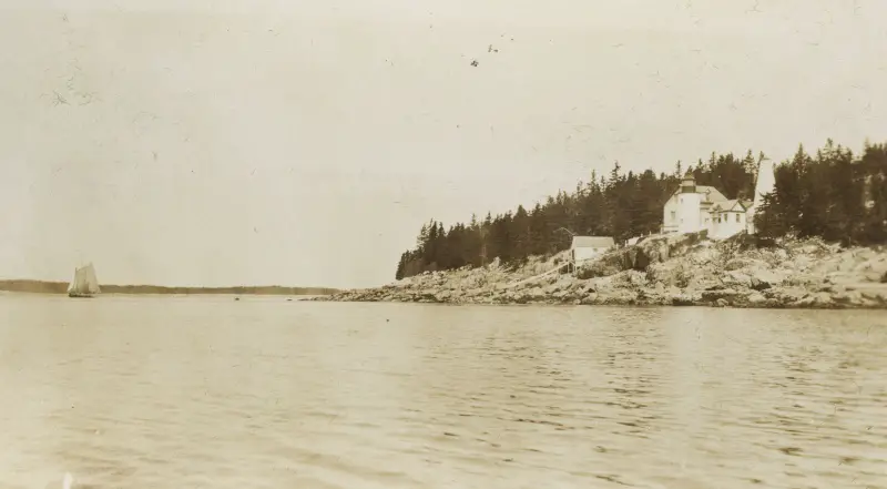 historic black and white photo of sailing boat and Bass Harbor Head Lighthouse in Acadia National Park