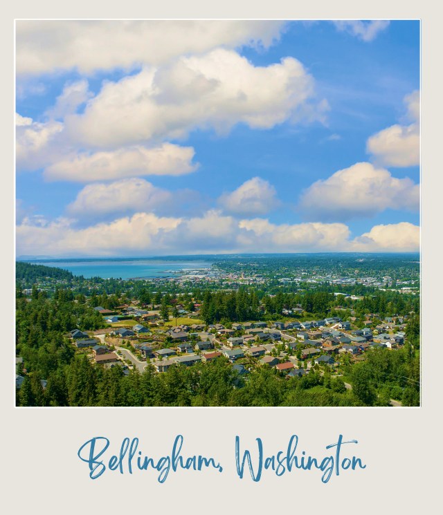 Aerial view of buildings in Bellingham, WA, surrounded by trees and mountains as background during a cloudy day near Bellingham International Airport