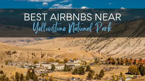 Aerial view of buildings surrounded by mountains, brown grasslands, and trees, with the text, Best Airbnbs Near Yellowstone National Park.