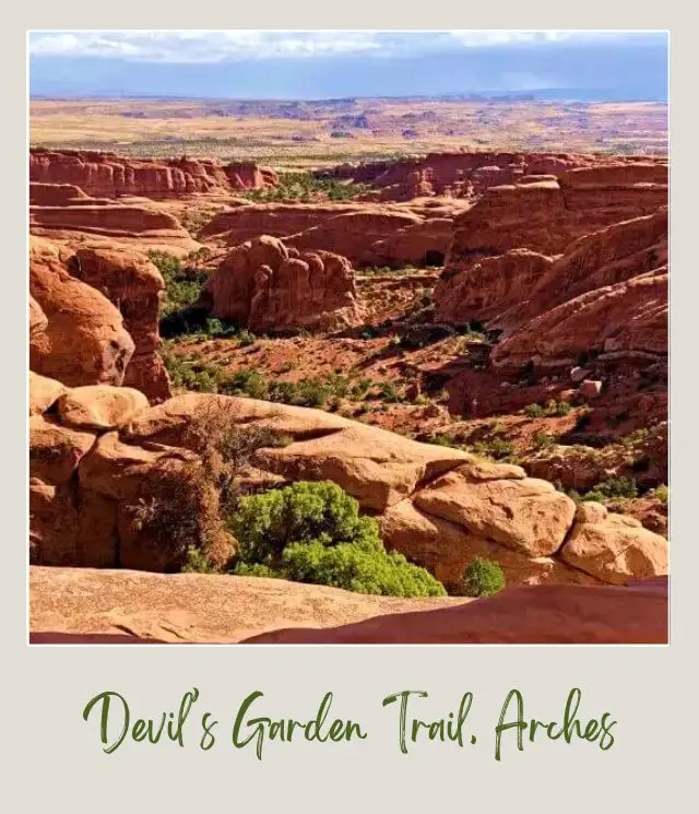 View of huge rock formations and bushes in Devils Garden Trail in Arches National Park.