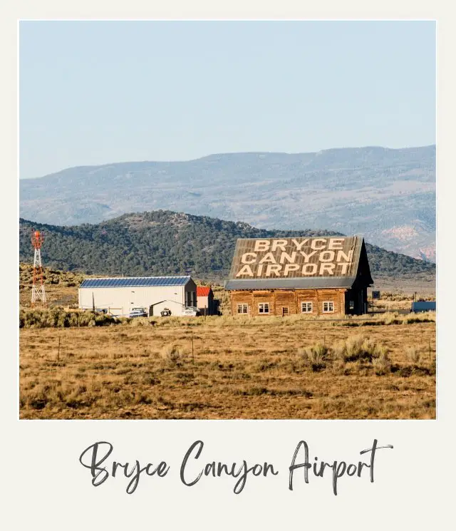 small log building with Bryce Canyon Airport written on roof plus two other low buildings with dry grass and small hills