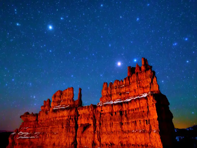 Huge reddish rock formation under the blue skies with stars at night in Bryce Canyon National Park