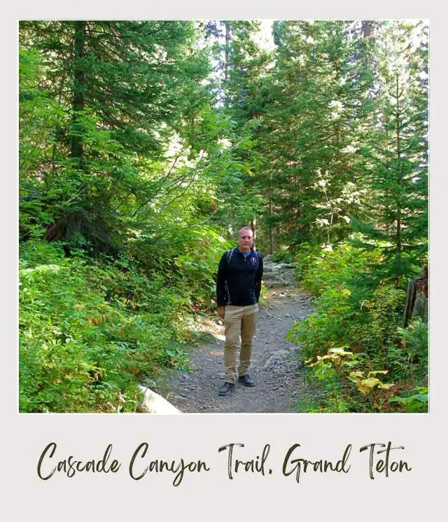 James standing in the middle of the Cascade Canyo Trail surrounded by trees and plants in Grand Teton National Park.