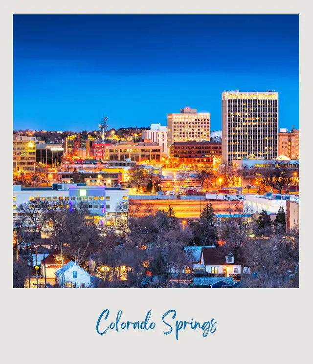 Brightened buildings surrounded by trees in front of mountains in Colorado Springs