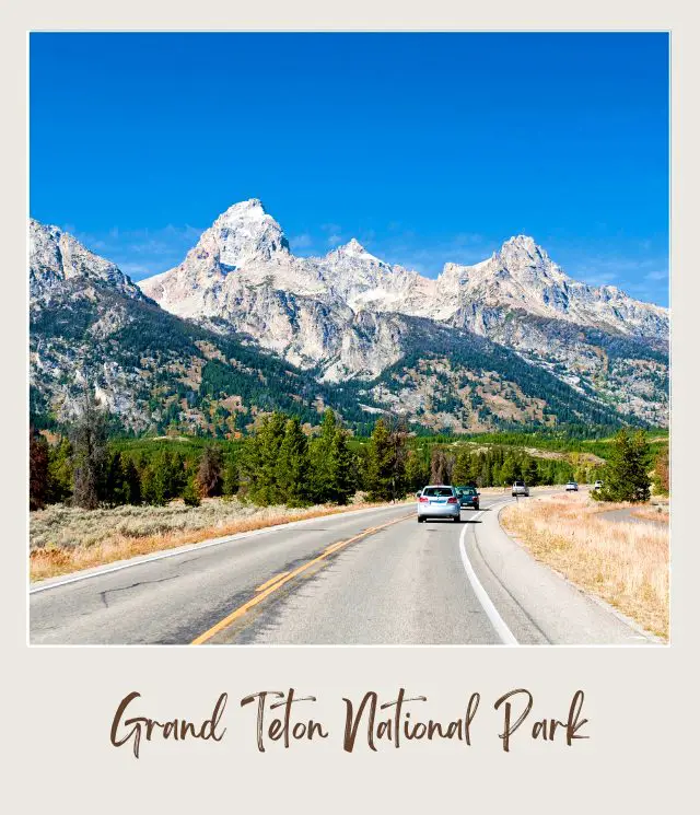 View of cars on the road and in the background are snow-capped mountains in Grand Teton National Park.