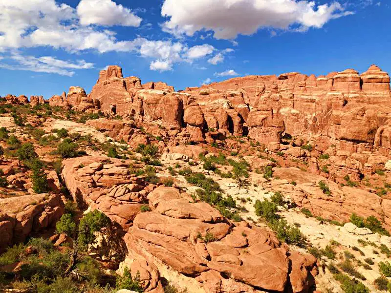 Huge rock mountains and bushes under the blue sky in Arches National Park.