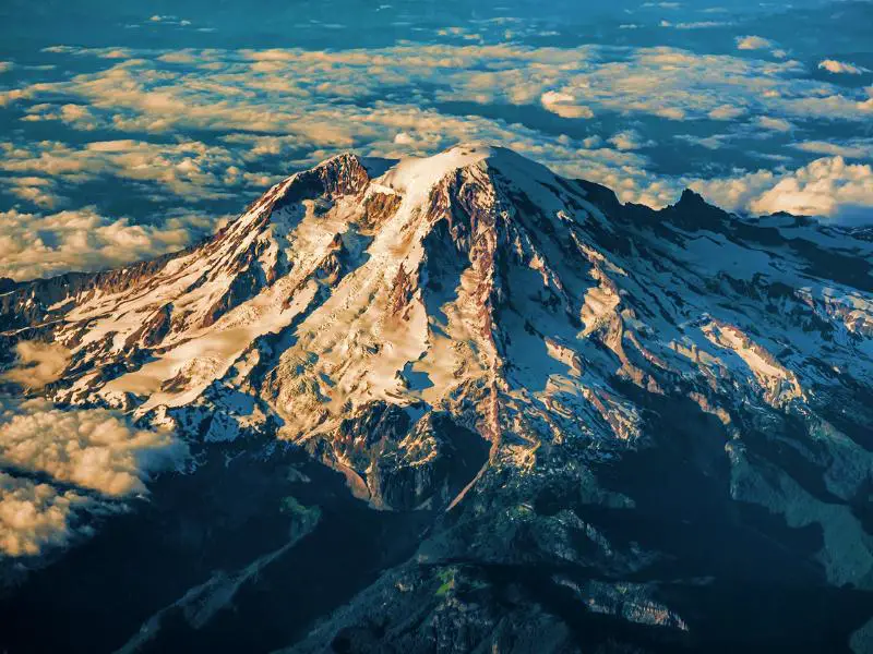 Aerial view of a snow-capped mountain surrounded by clouds in Mount Rainier National Park