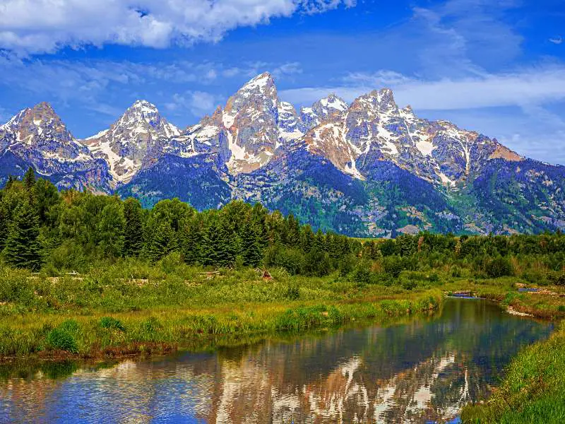 Trees surrounding the lake and behind are a snow-capped mountain range