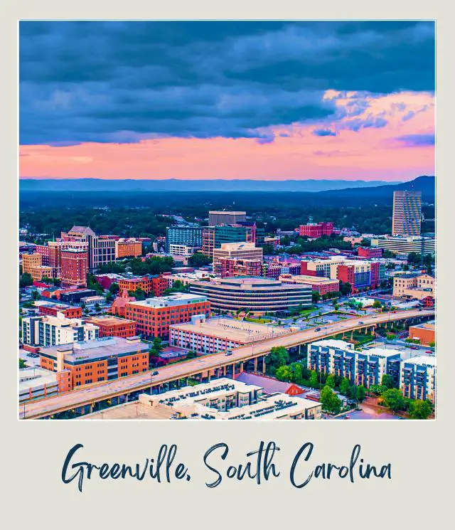 Bended road in the middle of the city surrounded by buildings and trees below the beautiful blue sky in Greenville, South Carolina.