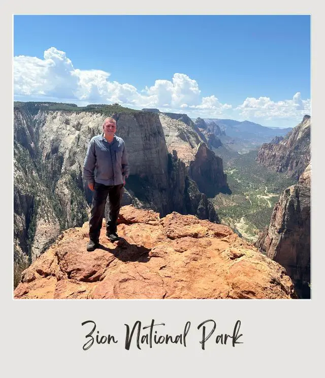 man standing on edge of cliff with canyon behind from Observation Point in Zion National Park