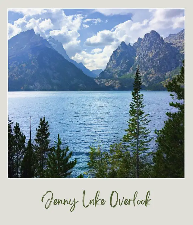 Blue lake is surrounded by trees and mountains on the cloudy day in Grand Teton National Park.