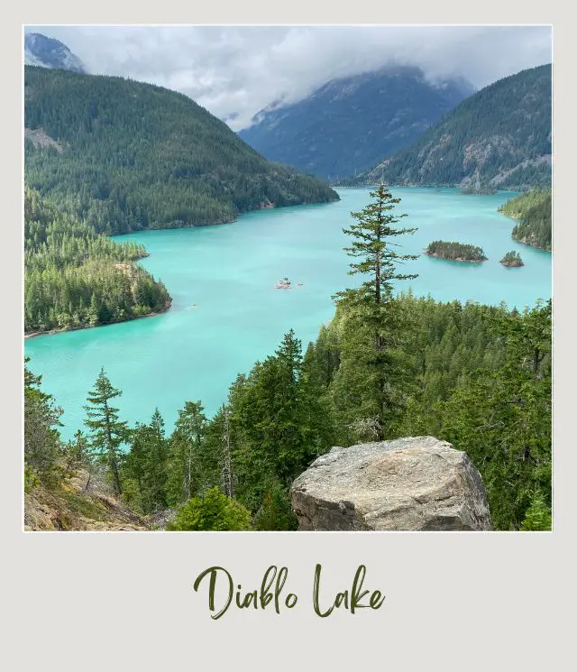 10 Fun Facts About North Cascades National Park View of blue waters surrounded with little green forests and a mountains in North Cascades National Park.