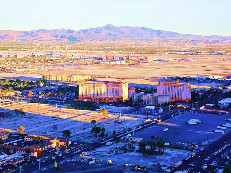 Mountains behind McCarran / Harry Reid Airport Las Vegas and at the forehand buildings are surrounded by trees beside the roads with several cars