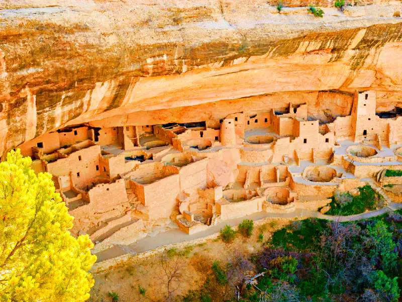 Rock cliffs and formations are surrounded by colorful trees in Mesa Verde National Park.