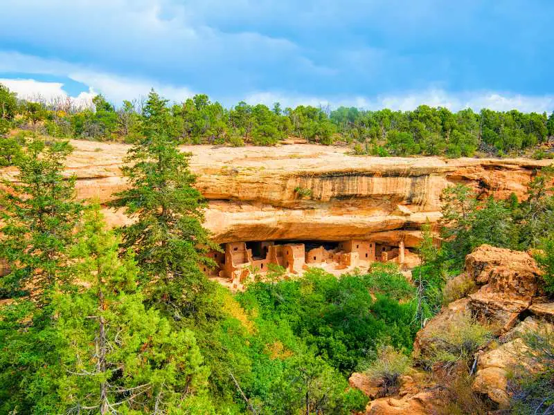 Rock cliffs and mountains surrounded by green trees in Mesa Verde National Park.