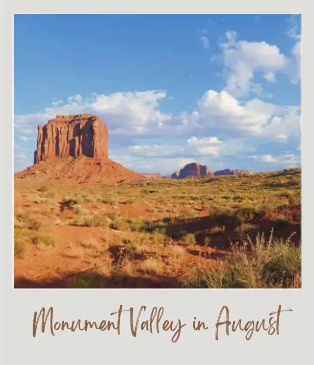 Visiting Monument Valley: What To Expect Throughout the Year View of rock formations and a plain field with bushes under the blue sky in Monument Valley.