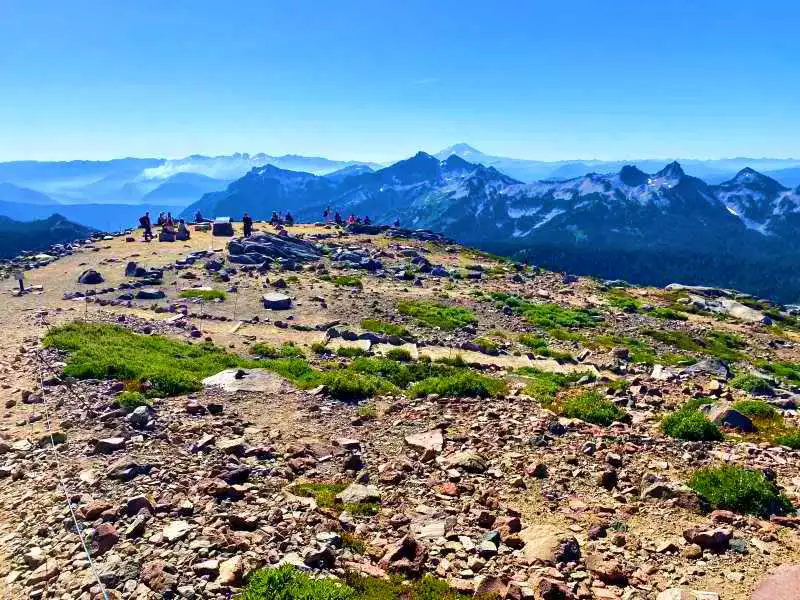 People standing on the rocky mountains and in front of them are mountains in Skyline Trail Mt Rainier National.