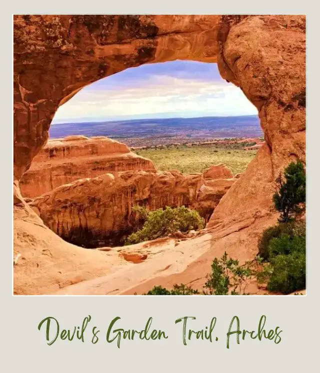 View of huge rock formations and mountains at the distance from the huge rock forming tunnel in Devils Garden in Arches National Park.