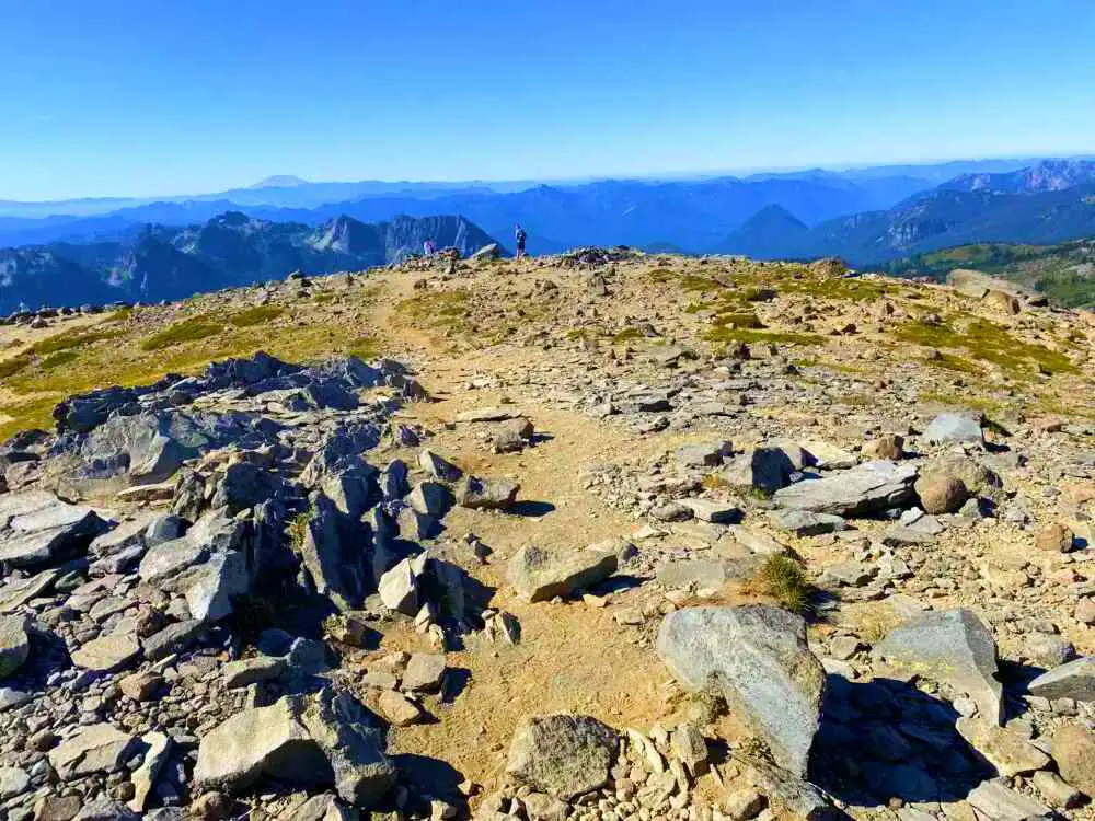 A man standing on the rock mountain and in front of him are mountains on Skyline Trail Mt Rainier National.
