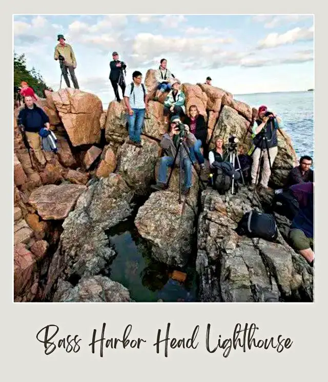 lots of people on rocks with cameras on tripods all waiting for sunset to photograph Bass Harbor Head Lighthouse in Acadia National Park