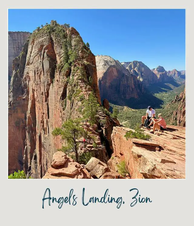 A photo of a rugged rock formations towering on either side and a couple sitting at the peak, enjoying the breathtaking views at Angels Landing, Zion.