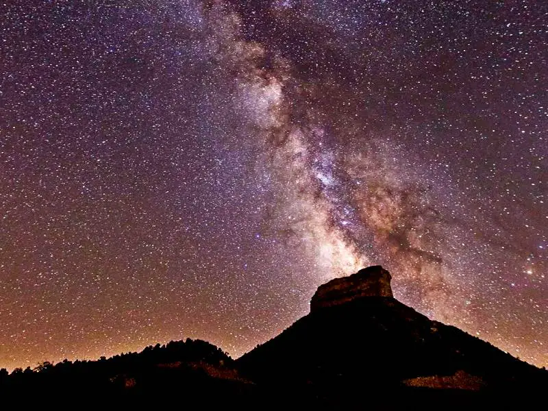 Rock mountains under the nights filled with stars in the nighttime in Mesa Verde National Park.