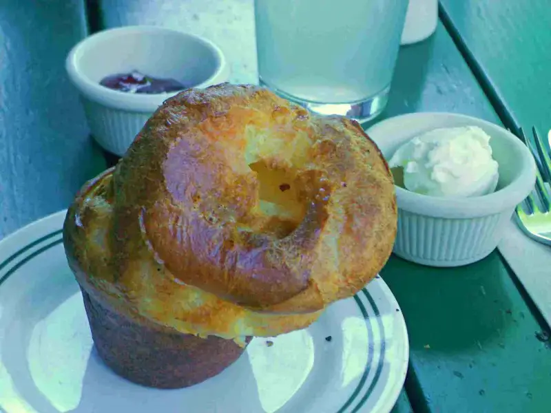 Brown popover in a plate, and besides are white bowls of cream in Acadia National Park.