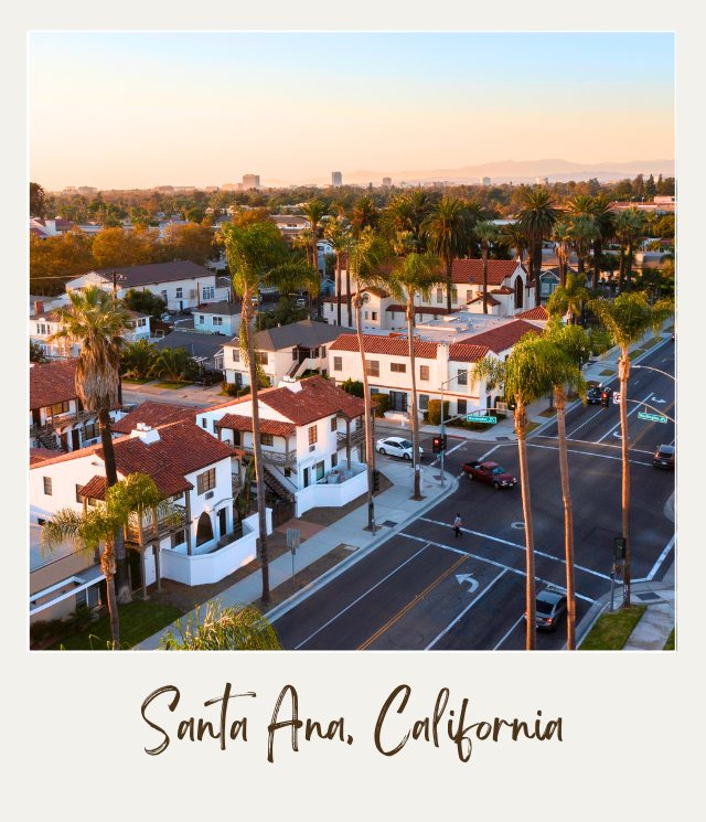 Roads with cars passing through in the middle of buildings surrounded by trees in the daytime in Santa Ana, California