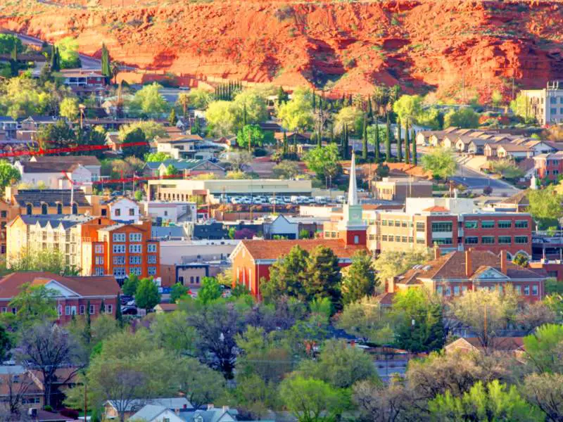 Buildings are surrounded by trees below brown hills in St. George, Utah