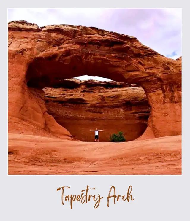 James standing on the huge rock formations and behind is a rock-forming "O" in Arches National Park.