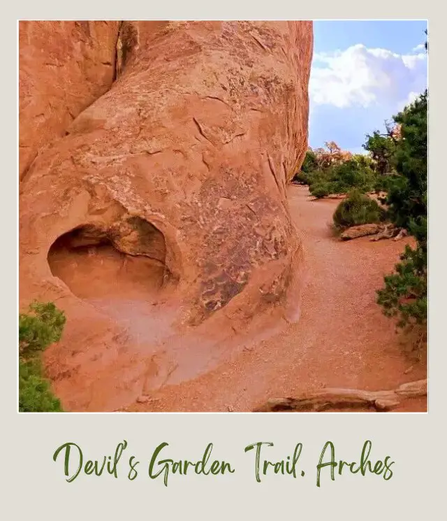 A trail to Devils Garden and beside are huge rock formations and bushes in Arches National Park.