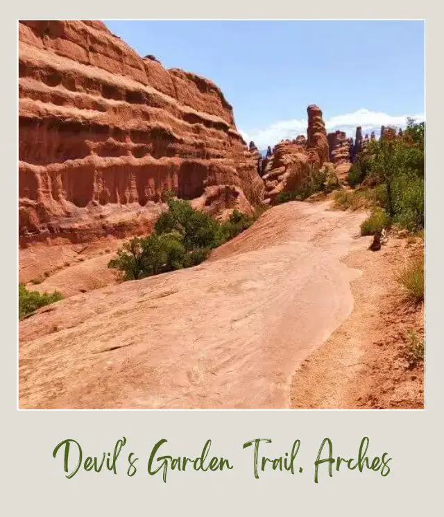 View of huge rock formations and bushes in Devils Garden Trail in Arches National Park.