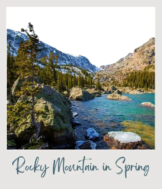 Visiting Rocky Mountain National Park: What To Expect Throughout the Year View of Snow-capped mountains, and below is a lake surrounded by trees and huge rocks in Rocky Mountain National Park.