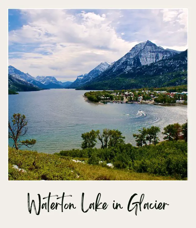 A Blue lake surrounded by mountains, trees, and buildings in Waterton Glacier National Park.