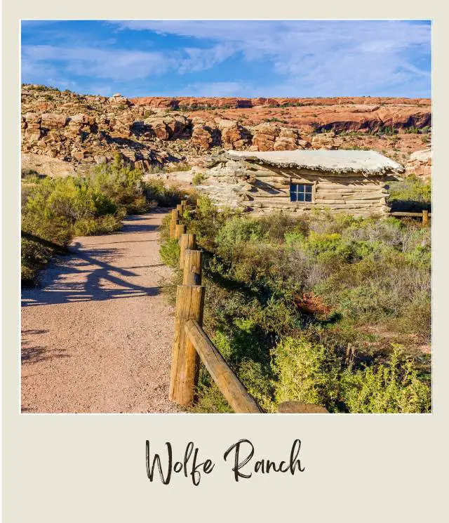 View of wooden cabin surrounded by bushes and rocks in Arches National Park.