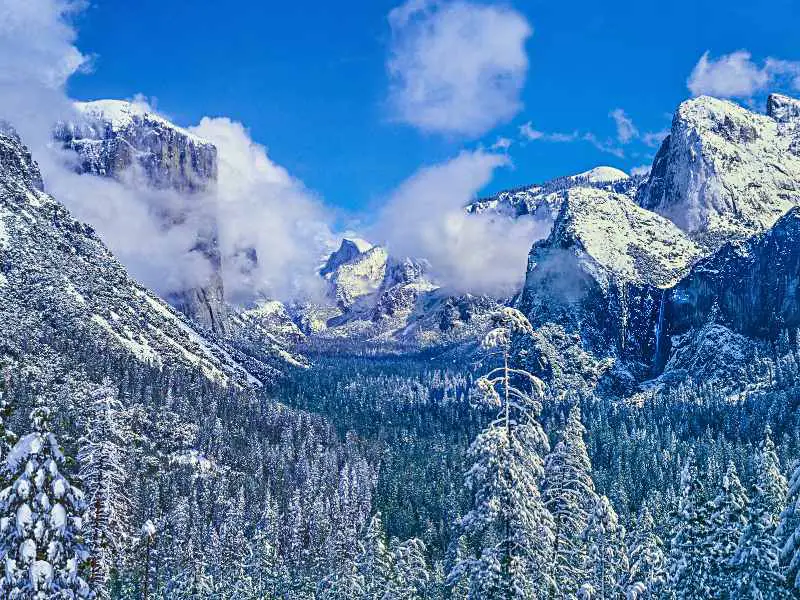 Aerial view of mountains and trees covered with snow in Yosemite National Park.