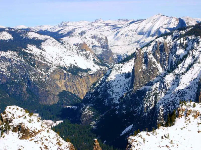 Aerial view of mountains and trees covered with snow in Yosemite National Park.