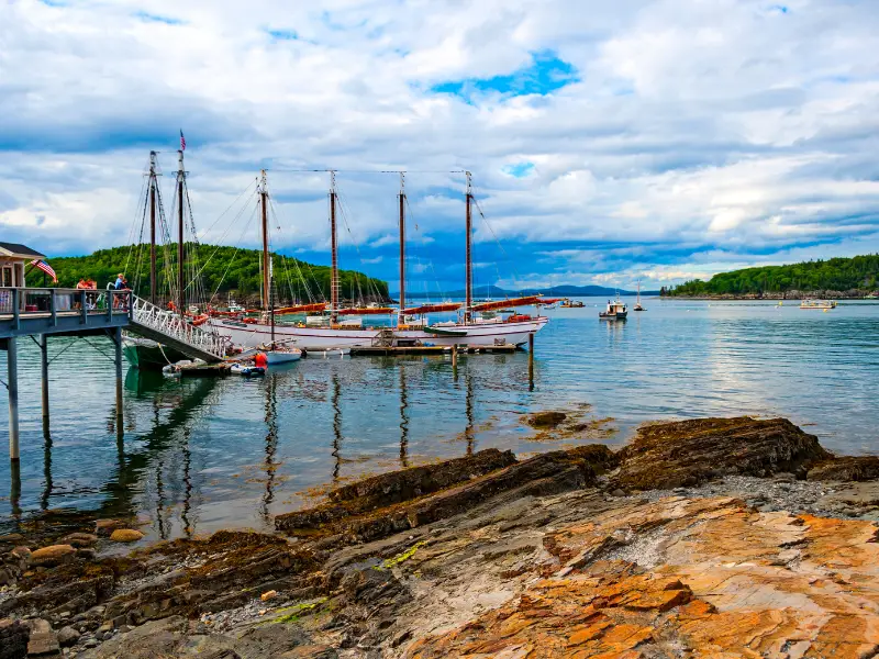 sailing boats surrounded by islands with rocks in foreground inbar harbor