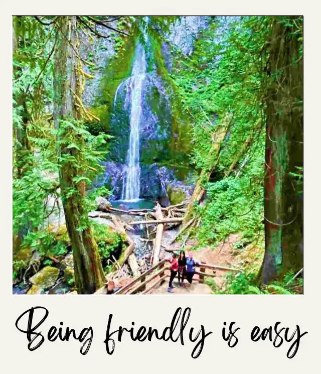 waterfall surrounded by trees with 3 people posing for a photo in front