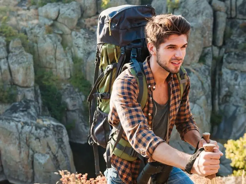 How to Use Trekking Poles: A Complete Guide for Hikers (With Pro Tips) young man hiking with a backpack