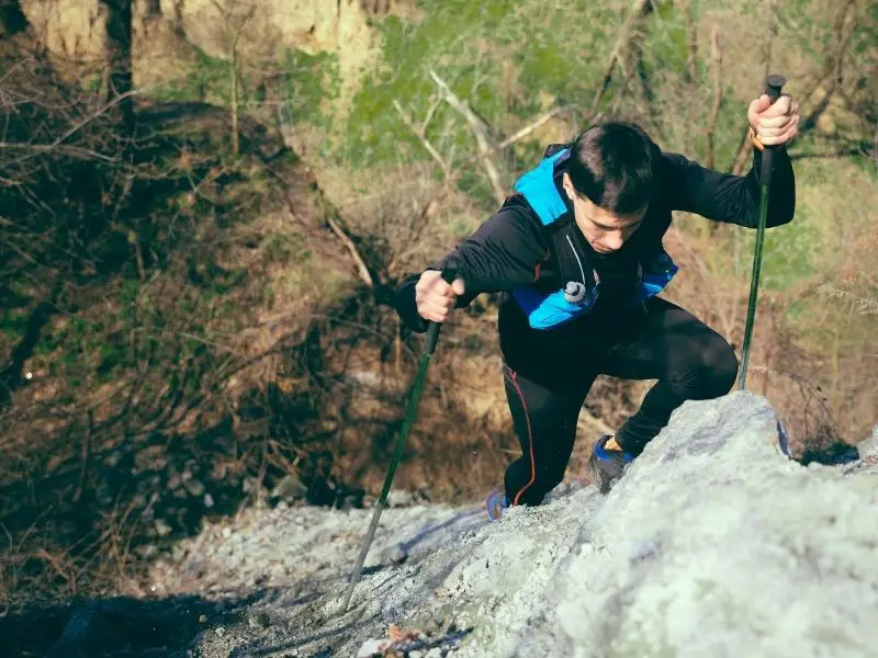How to Use Trekking Poles: A Complete Guide for Hikers (With Pro Tips) young man hiking uphill with hiking poles