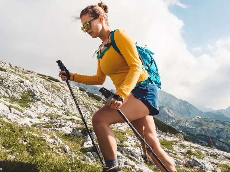 Pros and Cons of Trekking Poles: What You Need to Know young woman hiking with poles