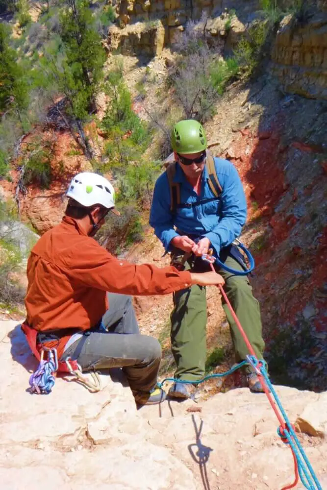 A person guiding another person in canyoneering in Zion National Park.